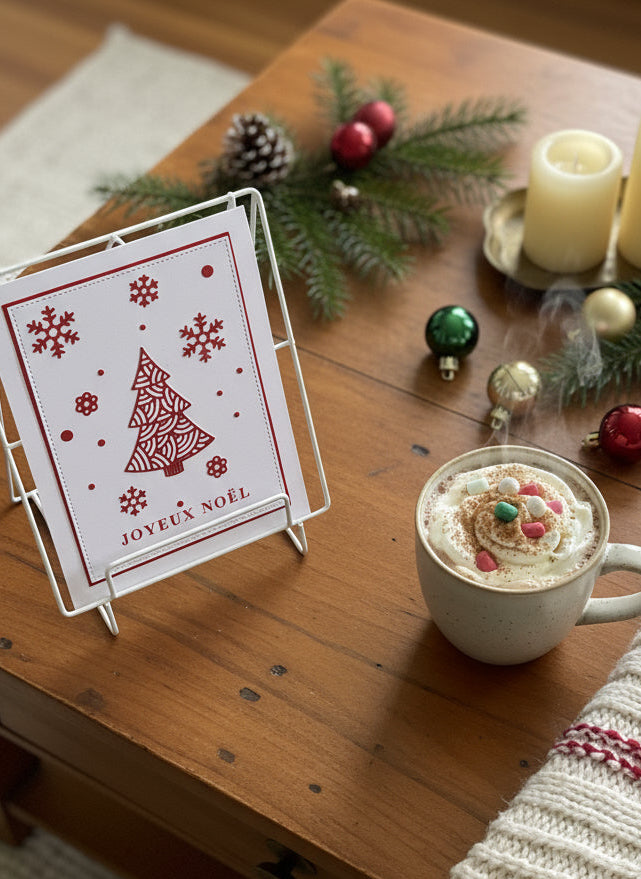 French Christmas card with red ornate tree and snowflakes with 'Joyeux Noël' greeting displayed with festive holiday decorations