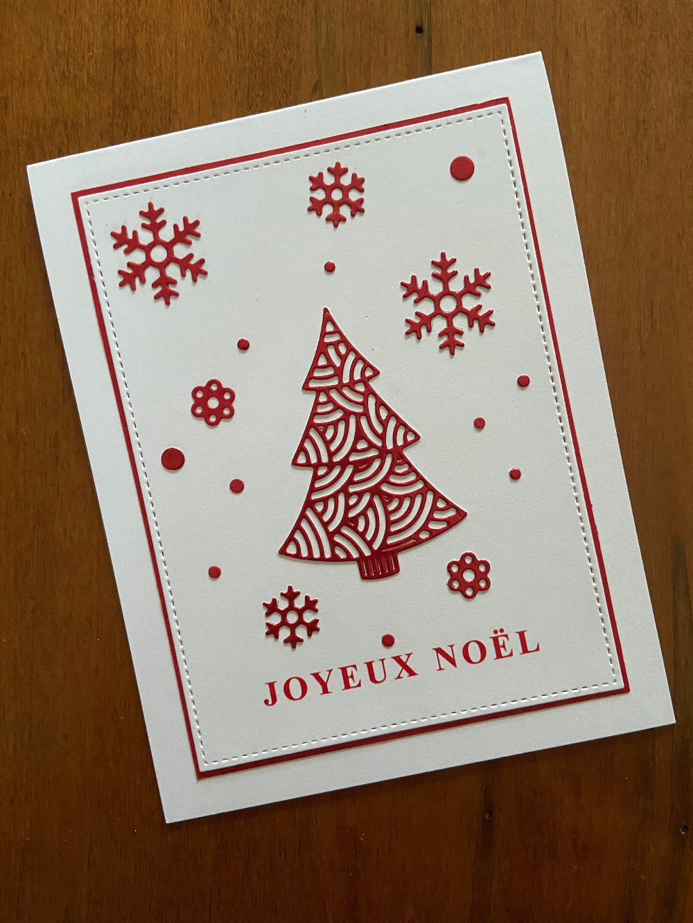 Handmade French Christmas card with a red ornate tree and snowflakes, and the text 'Joyeux Noël' on a white background.