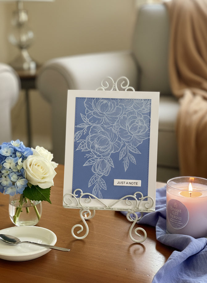White floral 'Just a Note' handmade card with cornflower blue panel with shimmer displayed on a decorated coffee table
