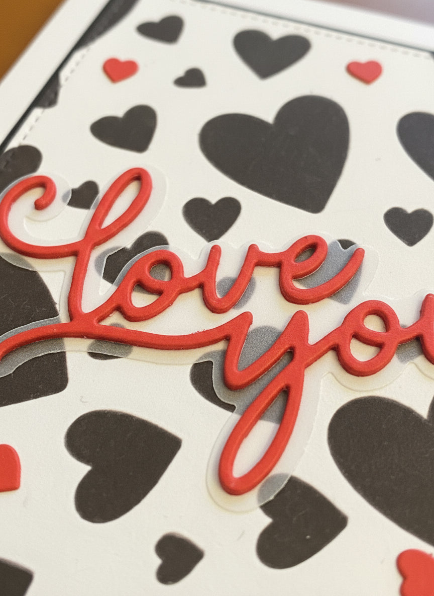 Close-up detail of love card showing layered red and black hearts with dimensional elements and modern typography