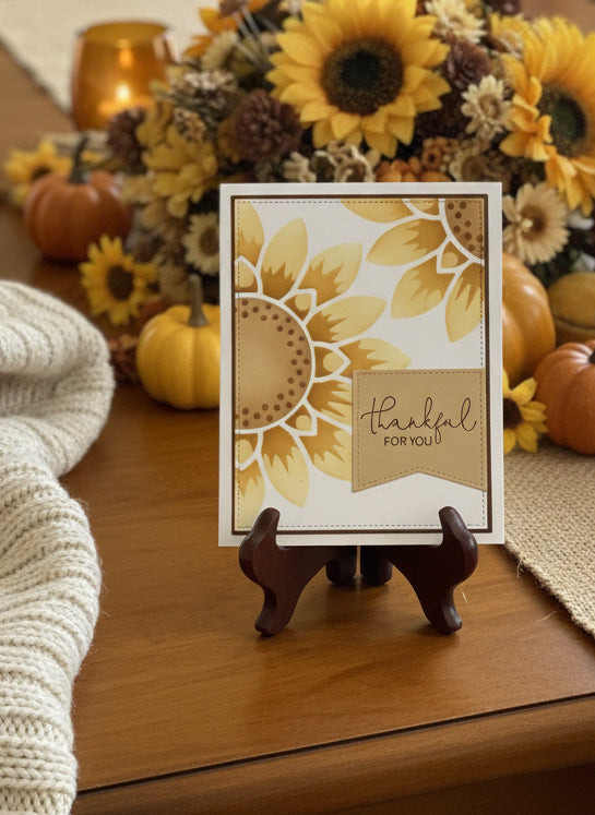 Thankful card with sunflower design on table decorated with pumpkins and sunflowers.