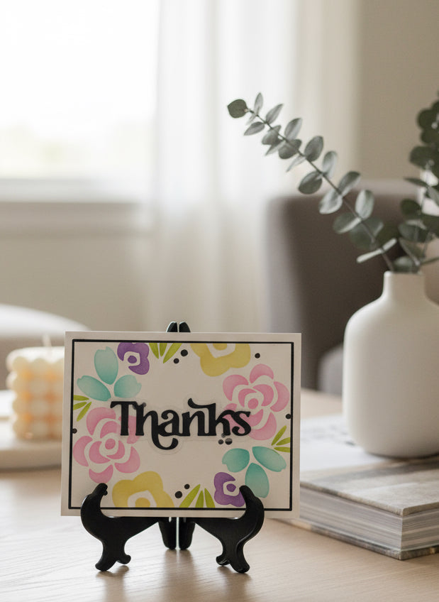 Pastel floral wreath card in a stand on a decorated coffee table. Text 'thanks in centre of wreath