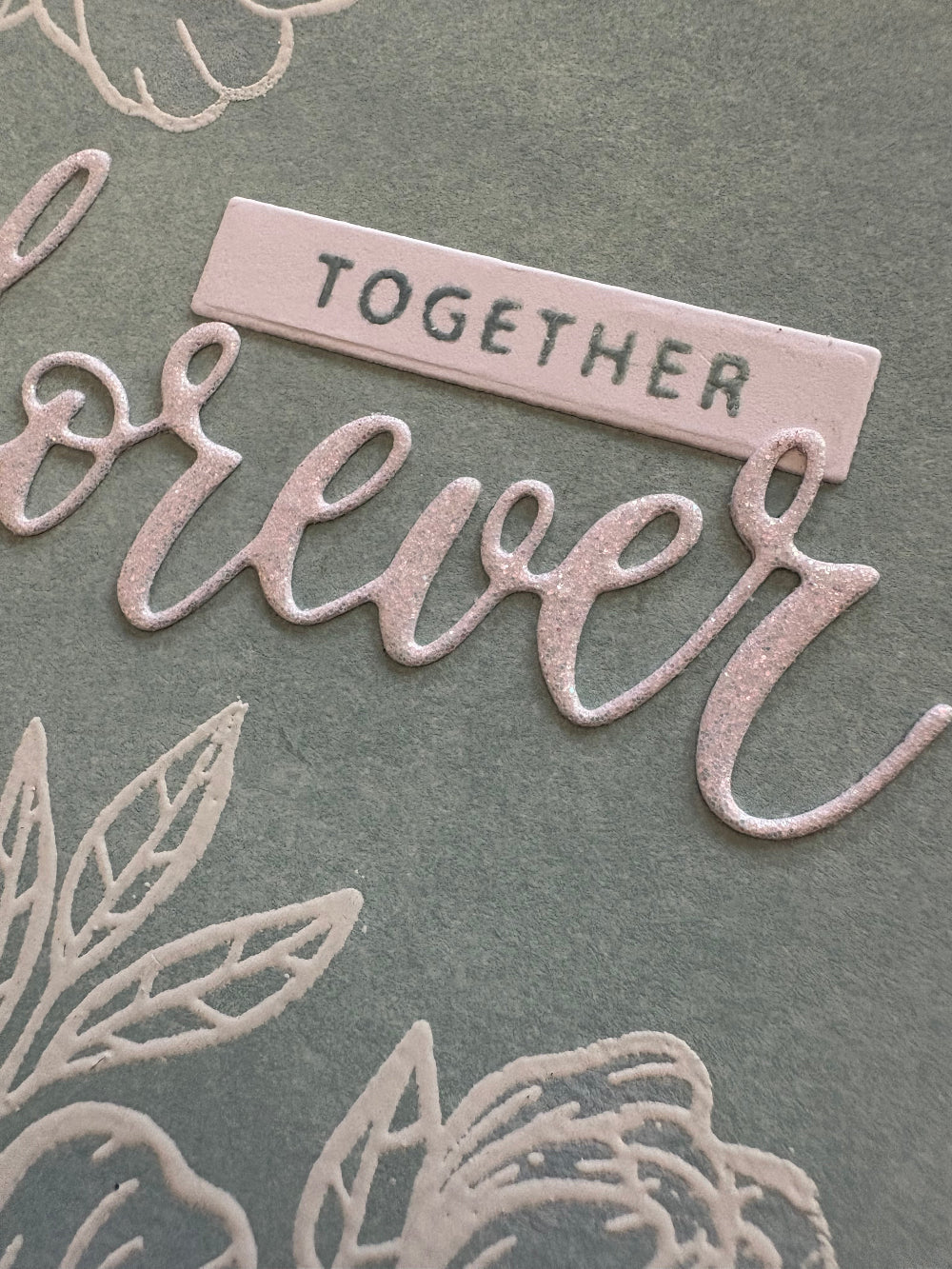 Close-up of handmade wedding card with 'Together Forever' sentiment and green decorative elements