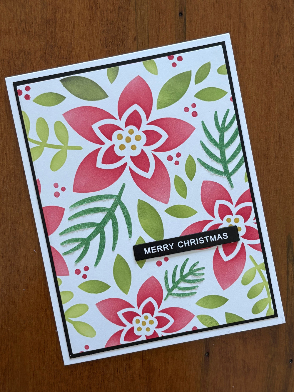 Modern floral Christmas card featuring contemporary poinsettia design with red blooms and green foliage on white notecard