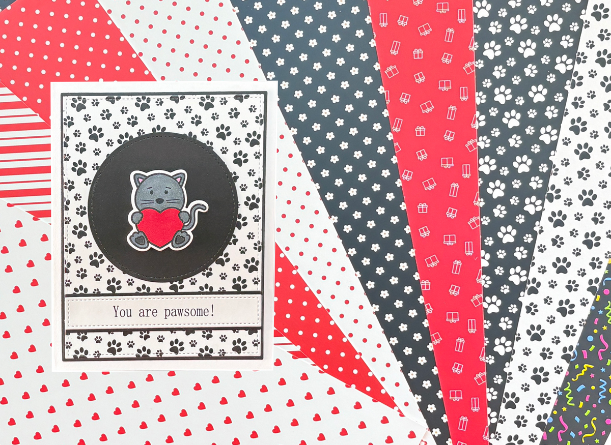Fan of premium patterned cardstock in red, black, and white designs, with a handmade "You are pawsome!" greeting card featuring a grey cat — Michelle V. Park Design