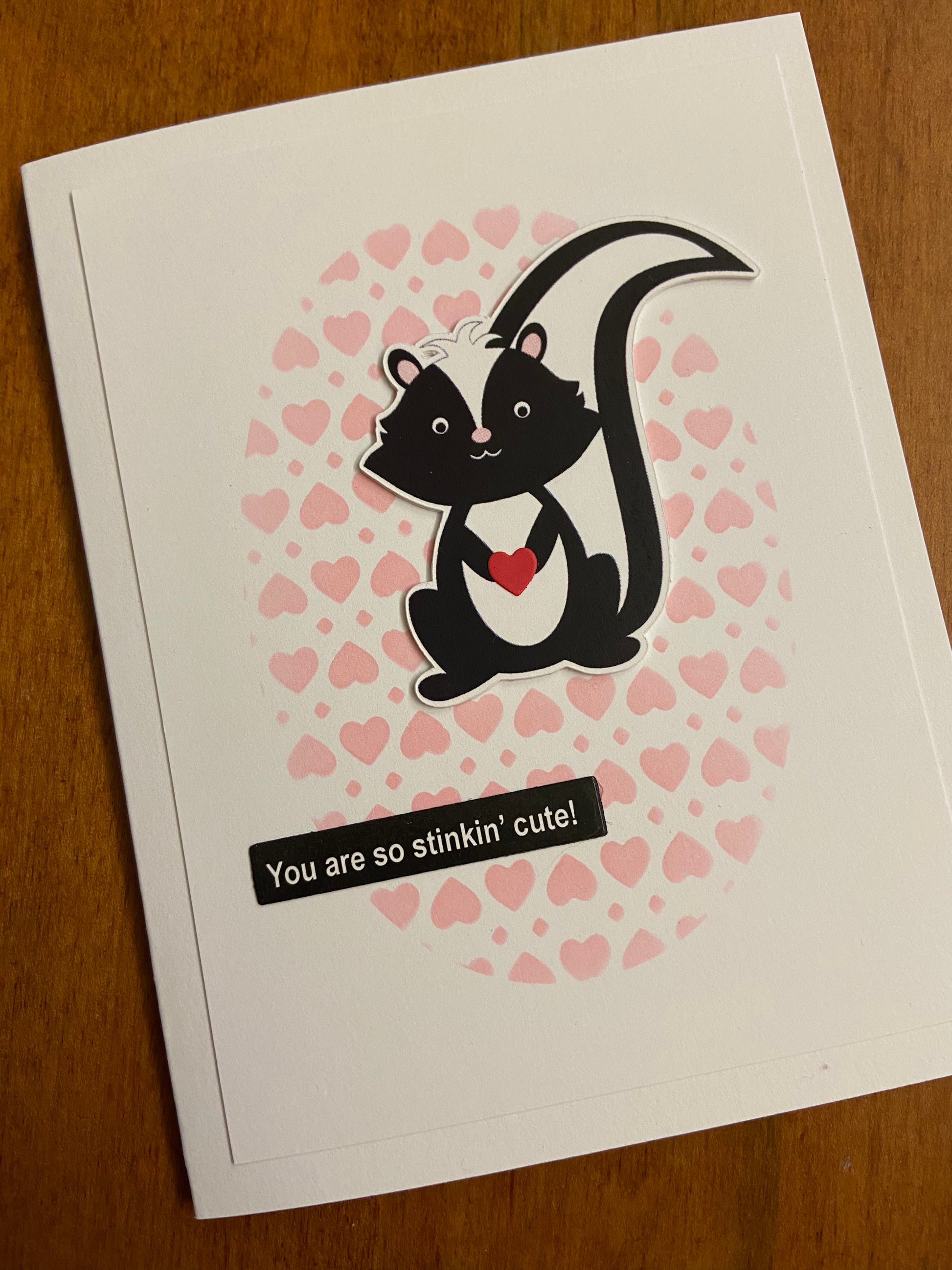 You Are So Stinking Cute handmade love or Valentines Day card. Cute die cut skunk focal image; pink stamped hearts in the white background. 