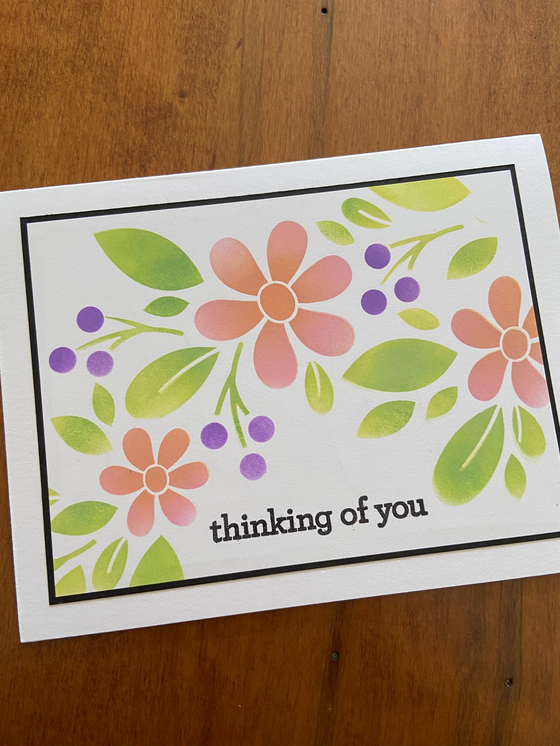 Floral thinking of you handmade card. Stencilled pink daisy like flowers with greenery and purple berries. 