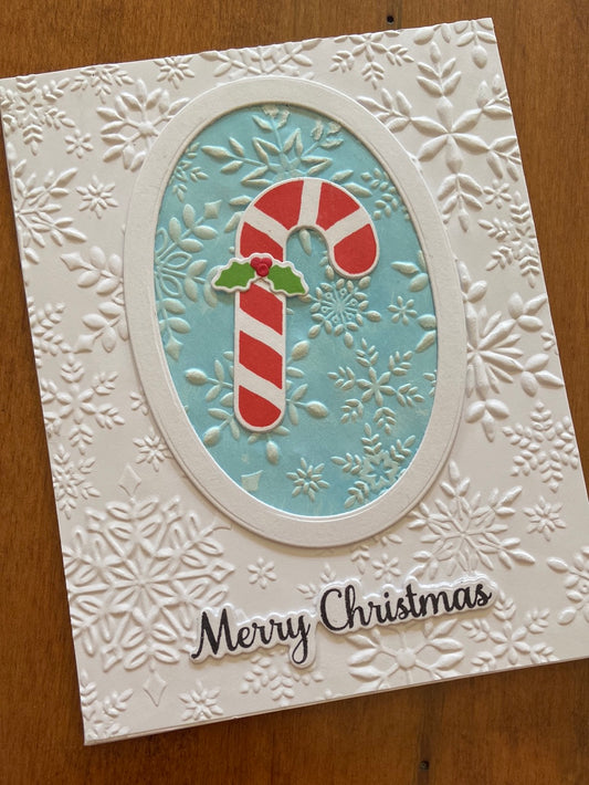 Handmade Christmas card with embossed candy cane, holly, and snowflakes design, and the text 'Merry Christmas' on the front.