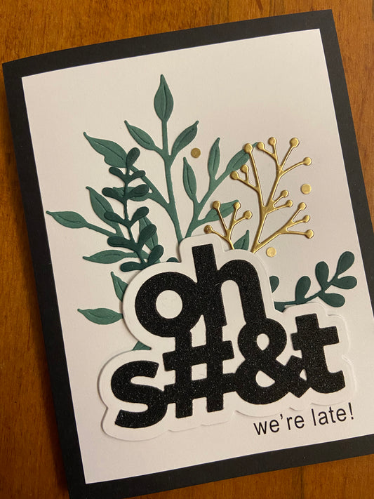 This card features an Oh S#&t die cut on black glitter card stock with a “we’re late!“ sub sentiment. Green foliage with a hit of gold behind the die cut adorns this card making this card sassy yet classy. A2 size card, white panel on a black notecard.